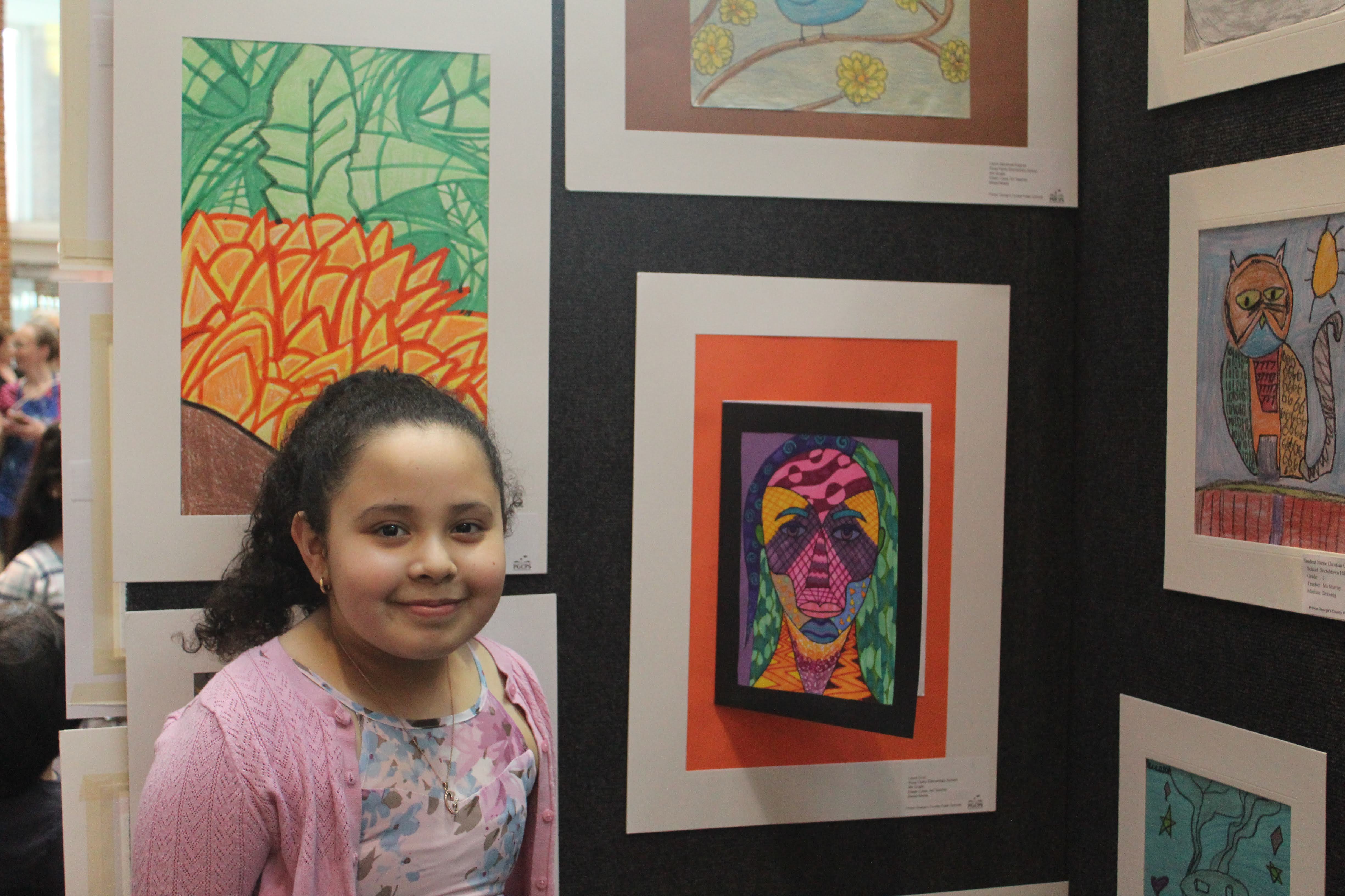 Laura Cruz from Rosa L. Parks Elementary School poses with her art at the PGCPS North County Art Show on Thursday, March 28, 2019. 
                Photo by Lillian Reese.